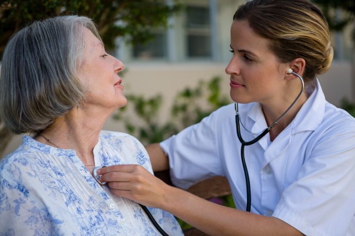 doctor listening to heart of older woman