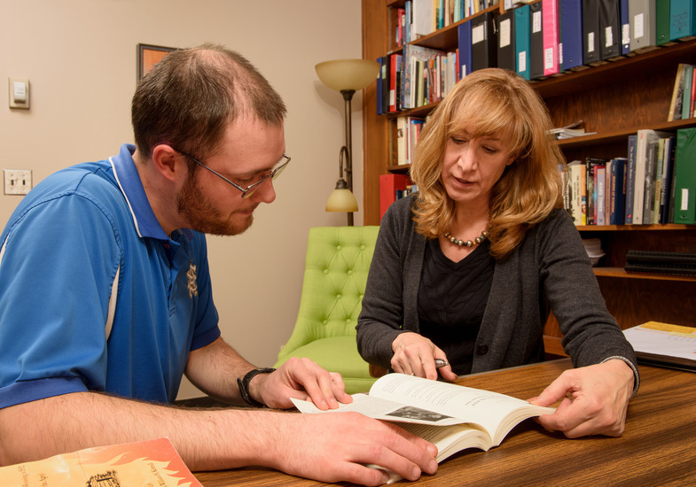 Photo of Professor Laegreid and student discussing a book 