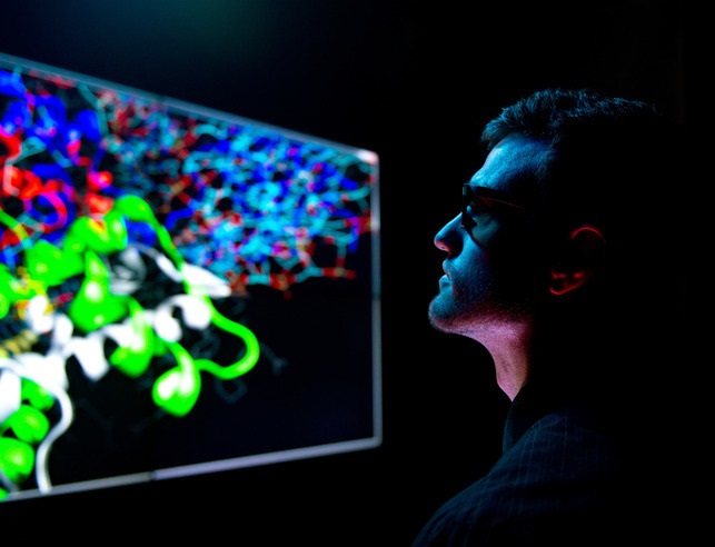 A student in a darkened room staring at a bright, colored screen.