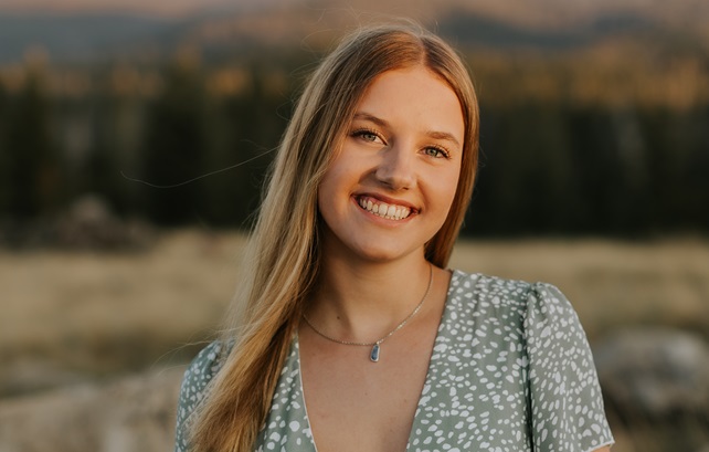 Emilia Hansen in front of a natural, blurred landscape wearing a green and white shirt.