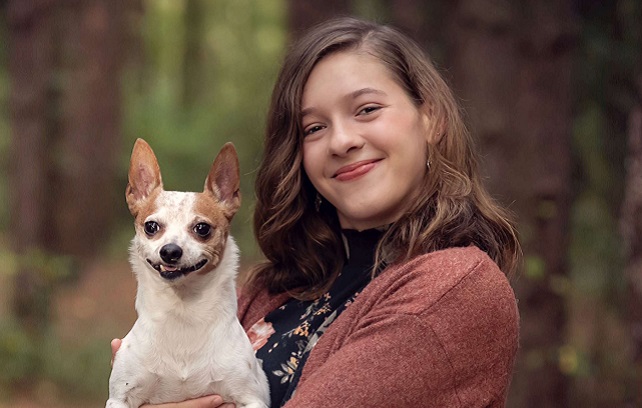 Samantha Killer wearing a maroon sweater holding a white and brown dog.