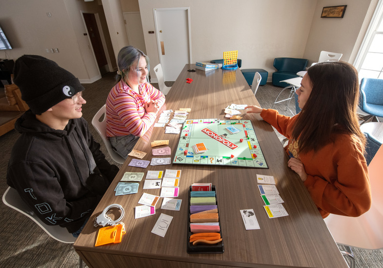 Tobin House residents sit at a table playing Monopoly.