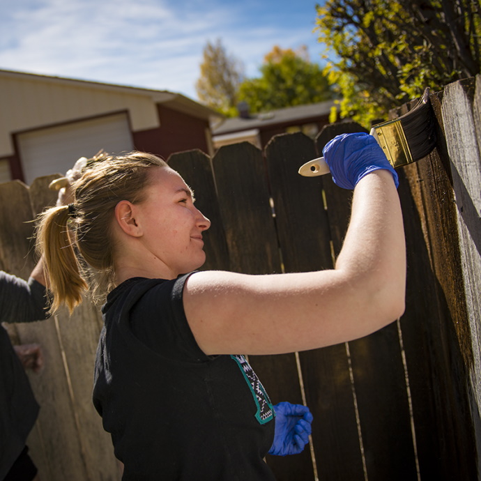 A student painting a fence