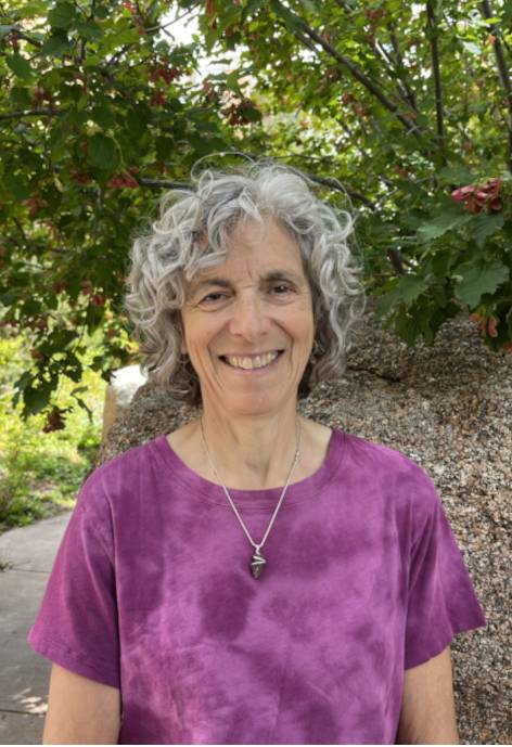 Meg Baalen-wood standing infront of a rock with a tree growing on it