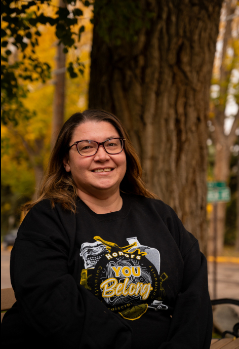 Cass Tolman wearing a black honors shirt outside in front of a tree