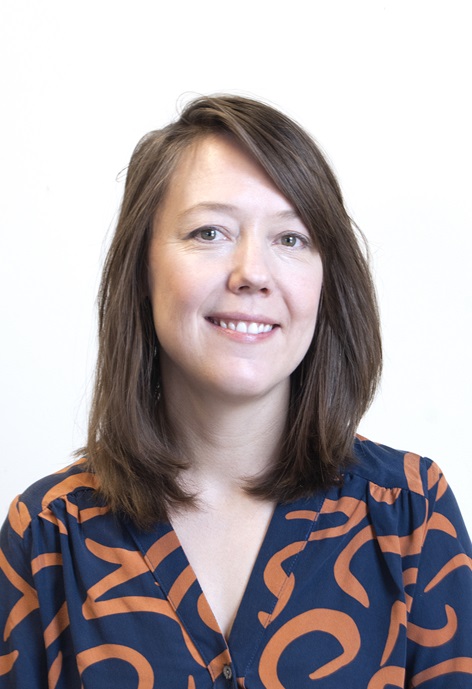 Tessa Dallarosa wearing a navy blue and orange patterned shirt in front of a white background.