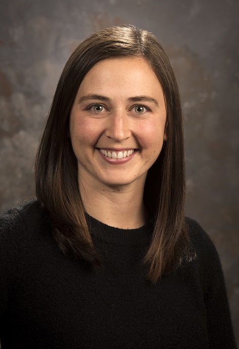Karagh Brummond wearing a black shirt in front of a gray background.
