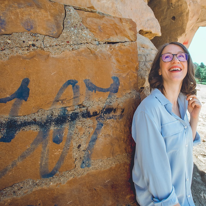 Janice Grover standing against a rock wall with painted numbers