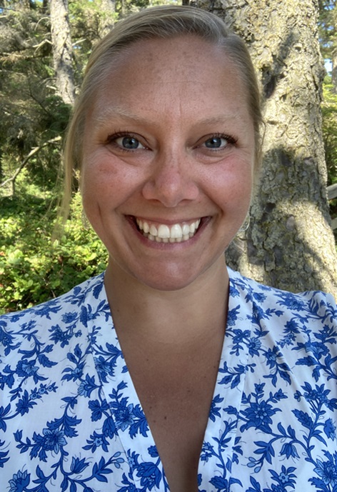 Ashleigh Pilkerton wearing a white and blue shirt in front of trees.