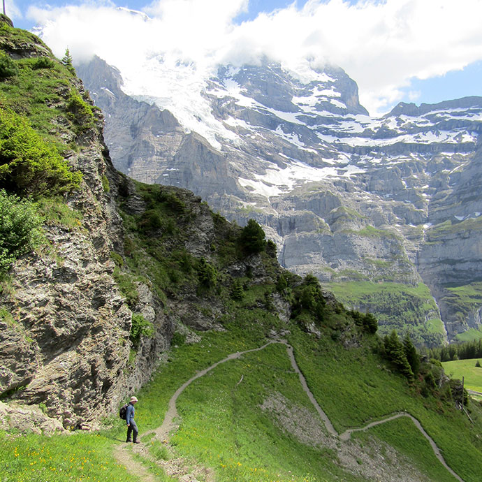 man on a mountainside near a trail