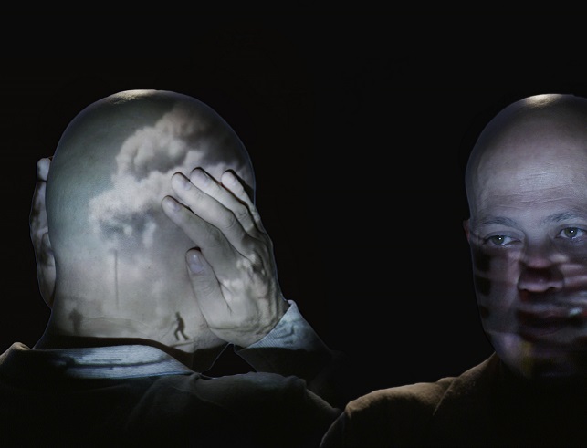 Two individuals facing each other with ambigious lighting with one covering their ears.