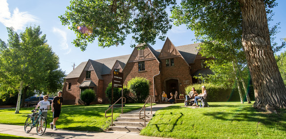 Two students walk on the sidewalk in front of the Guthrie House.