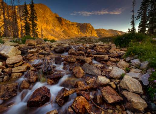 Snowy range rocks with river water trickling through the rocks with landscape in the background