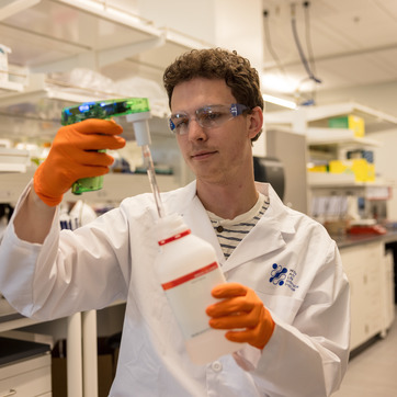 Student in a white lab coat conducting an experiment