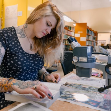 A person researching using a notebook and microscope.