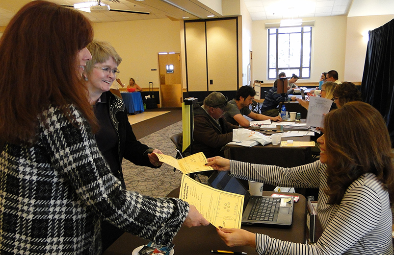 Payroll Specialist handing employees forms at a benefits fair.