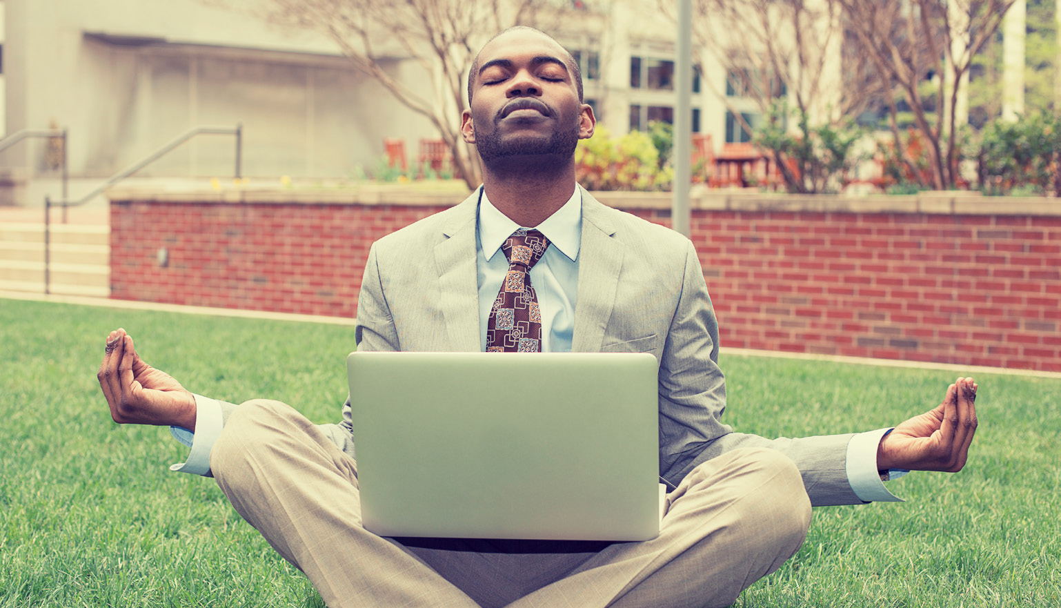Man holding a laptop while meditating