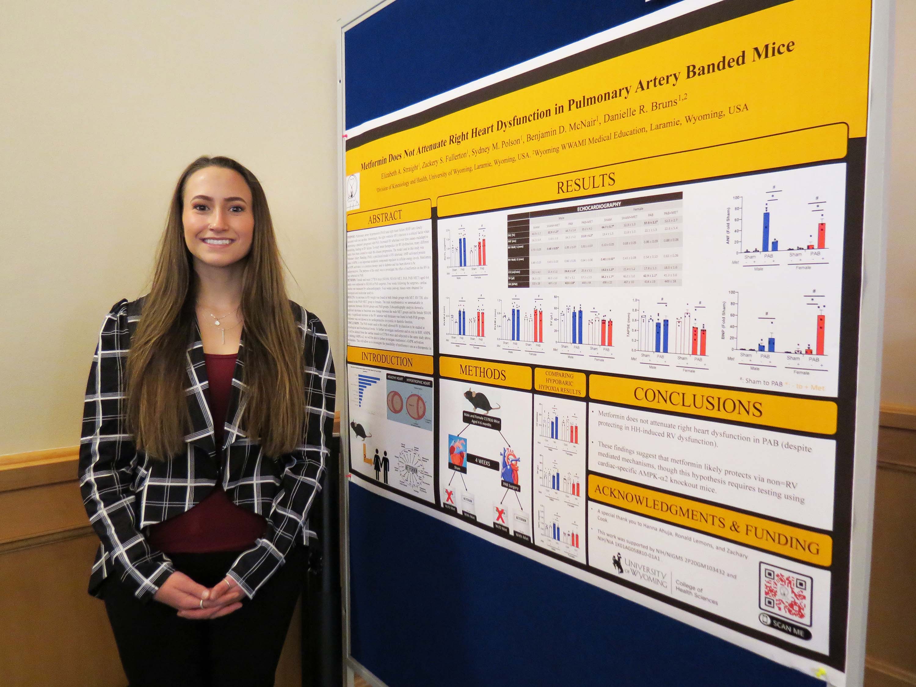 Female student standing in front of a research poster.