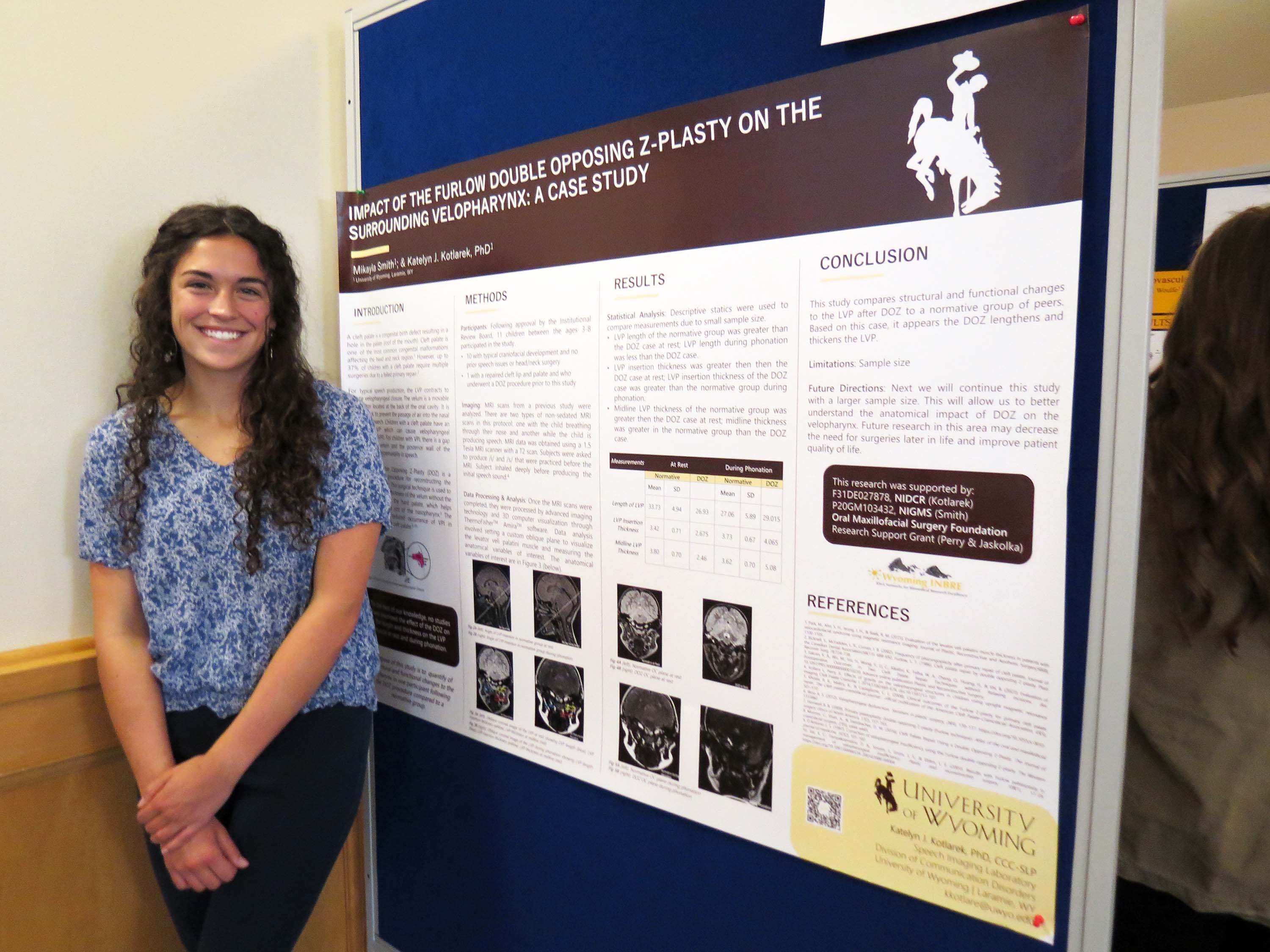 Female student standing in front of a research poster.