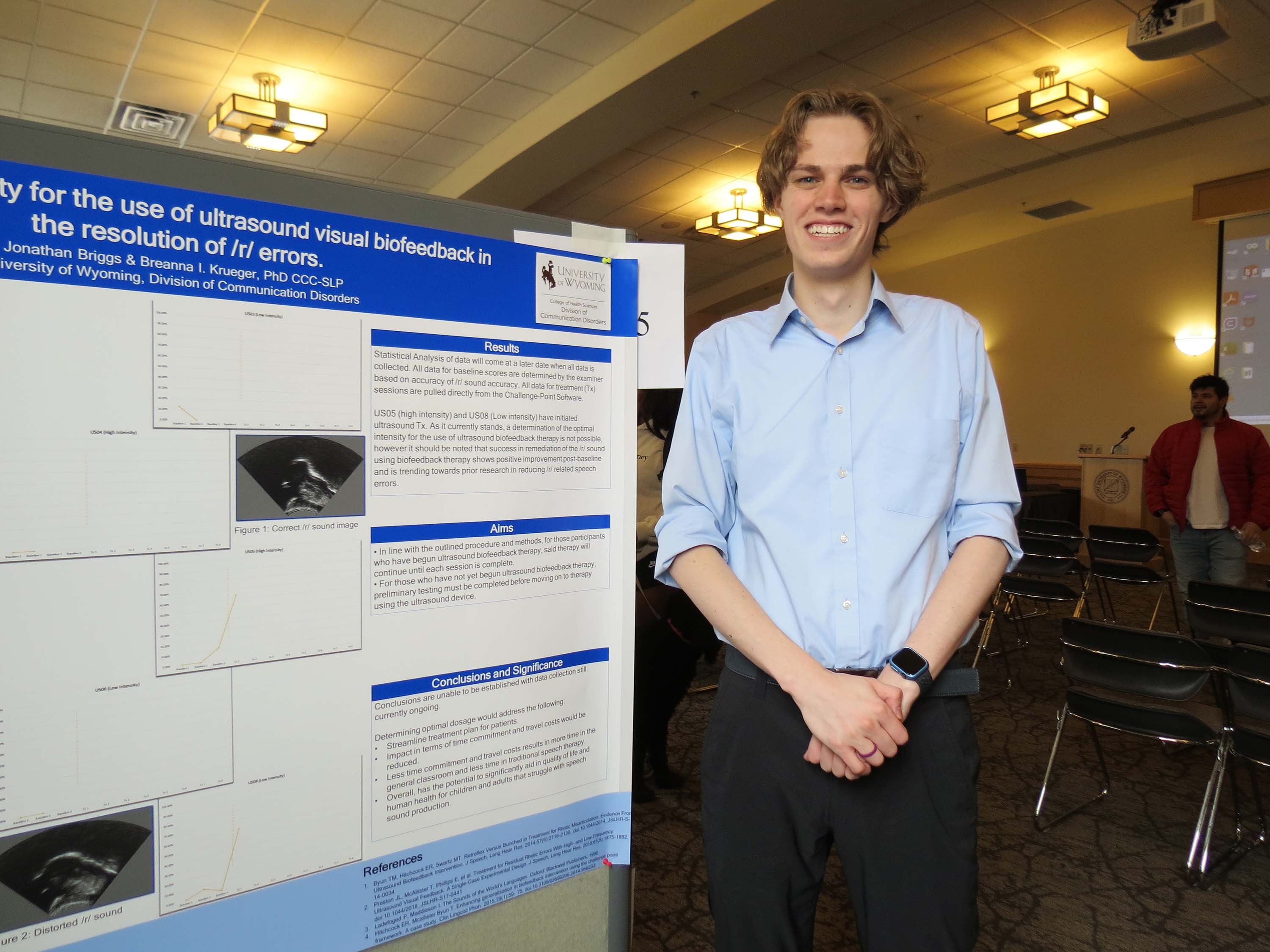 Male student standing in front of a research poster.