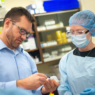 A person in scrubs looking at a pharmacy tool.