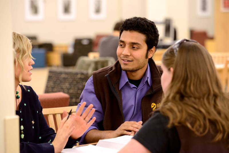 Man speaking with students at a table.
