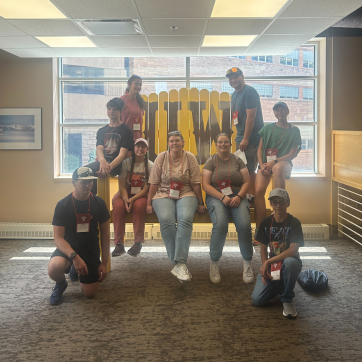 HSI students sit on a large yellow lawn chair with UW written on the chair