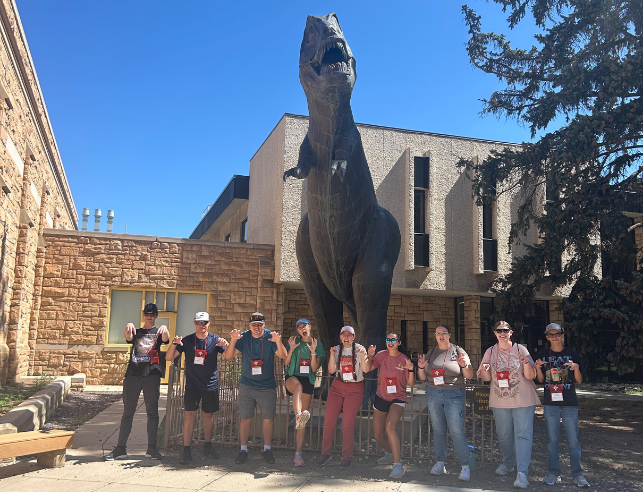 Students in front of the dinosaur on campus.