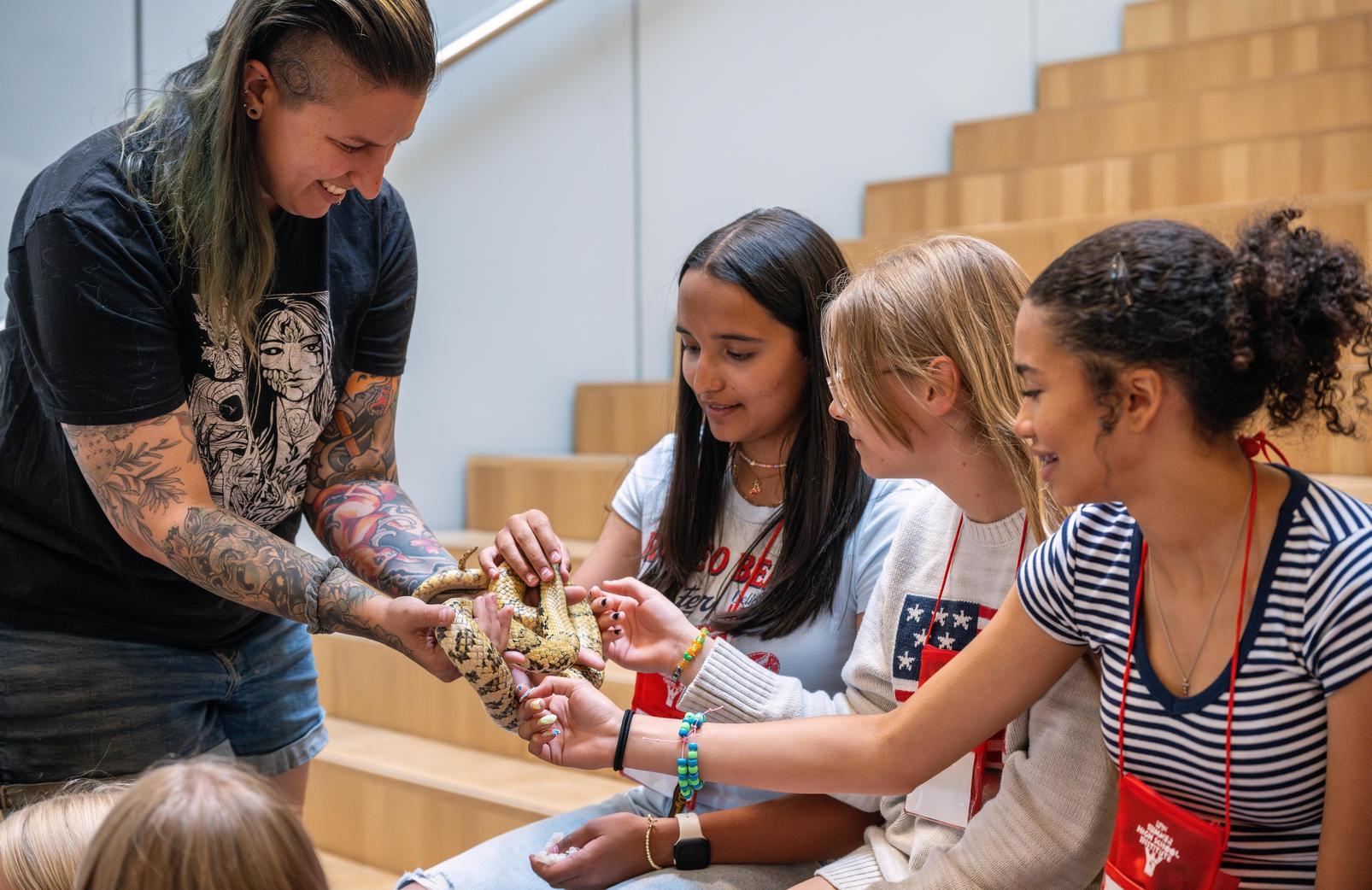 Students holding a snake during their STEM showcase.