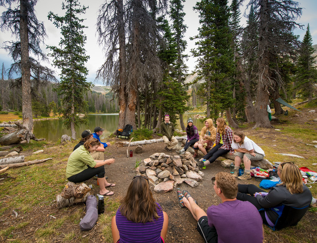 Students sitting around a campfire in the mountains