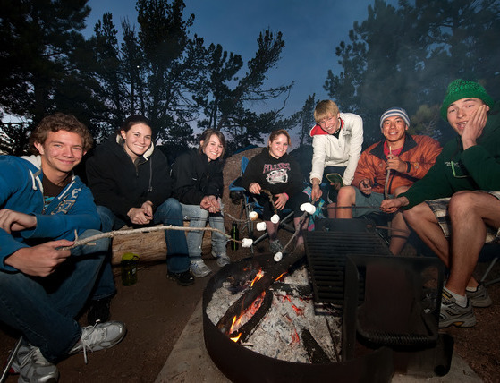 Students around a campfire roasting marshmallows.