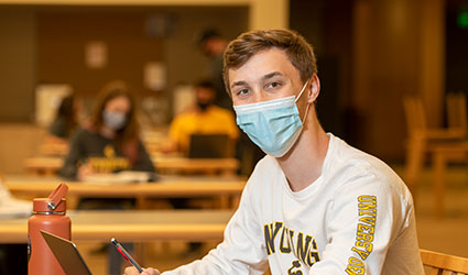 Man in mask sitting at a desk
