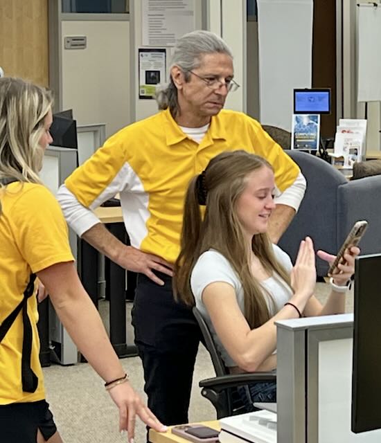 photograph of Service Center employee helping out two students