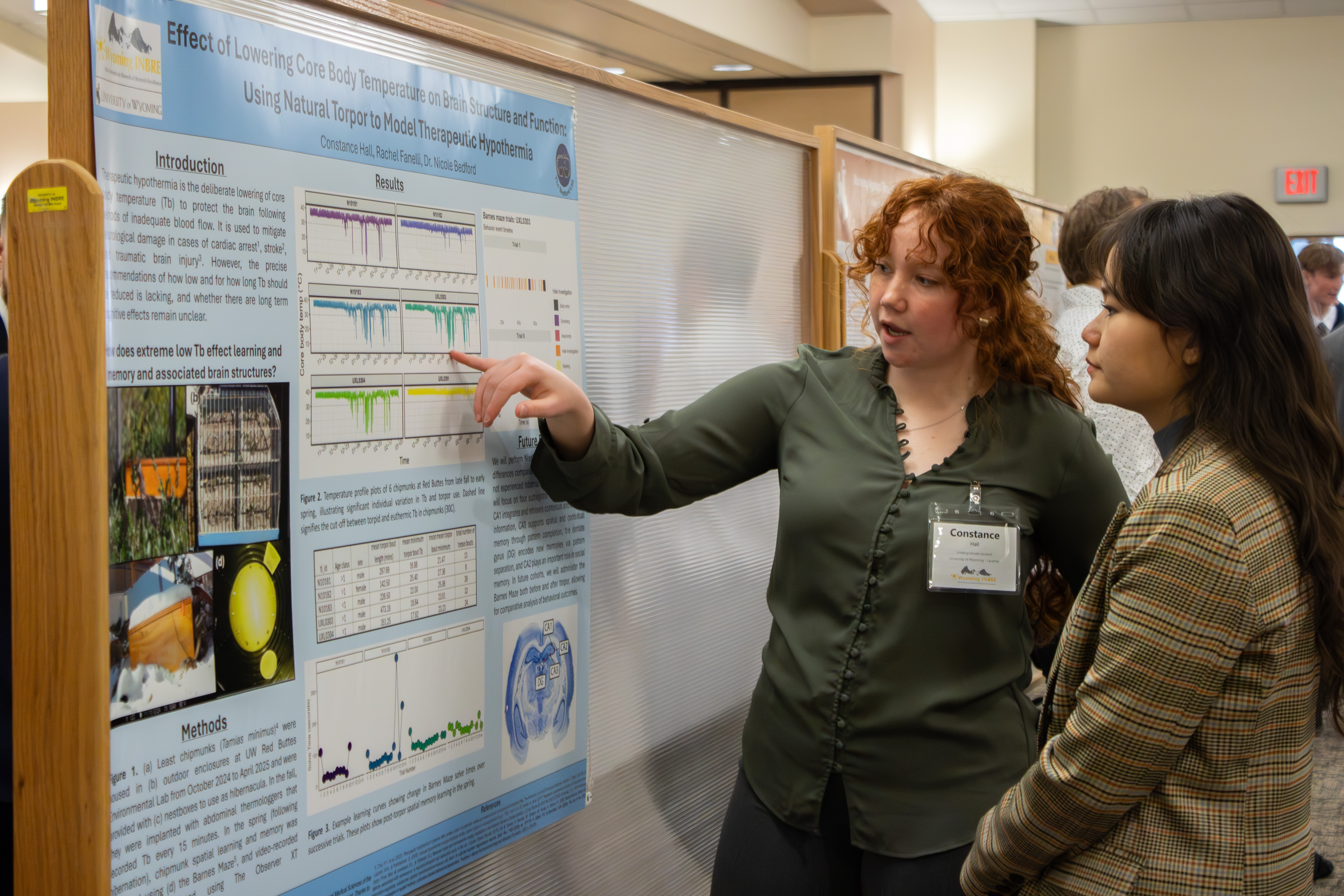 two women stand in front of poster visiting