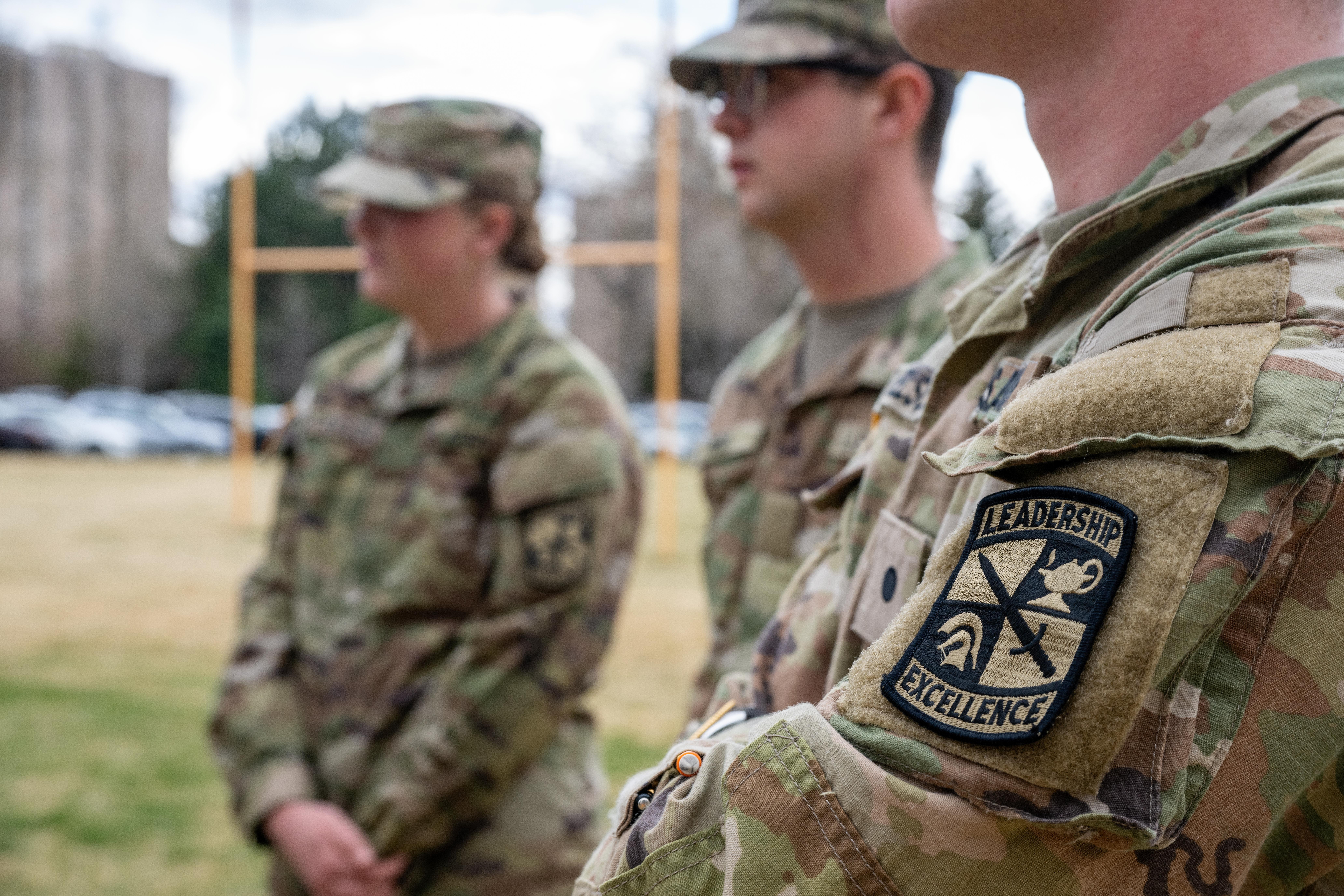 three men stand in military attire