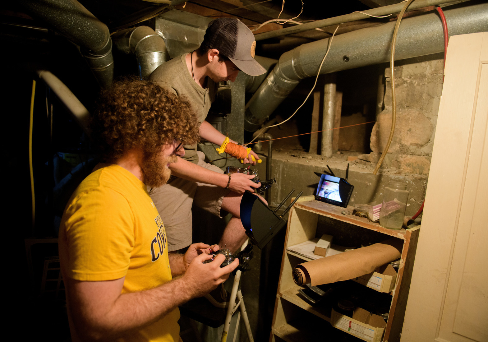 two students in a dark service tunel look at a small screen