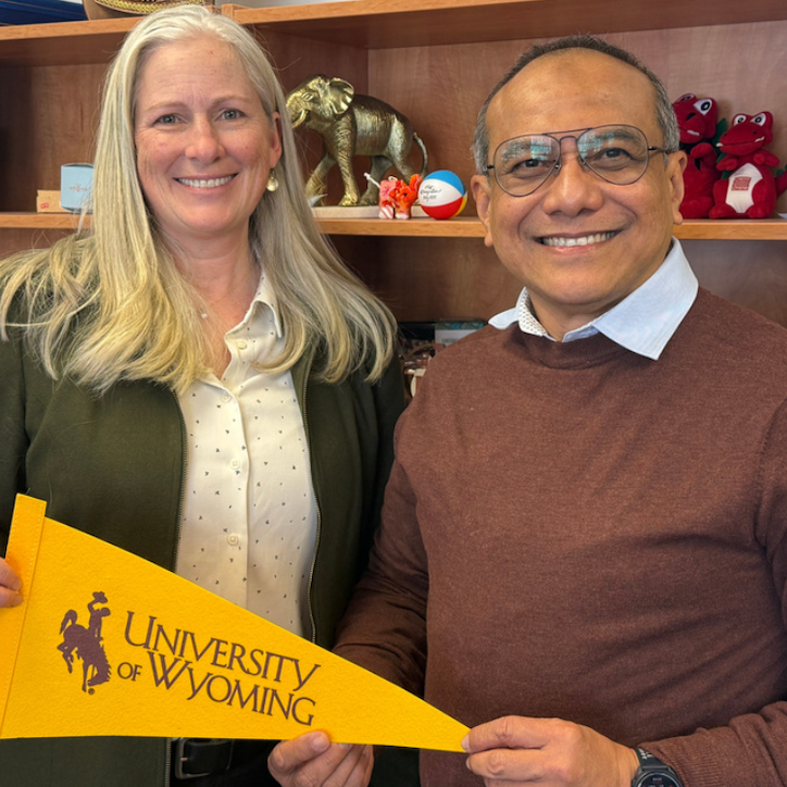 two faculty smiling with UW flag