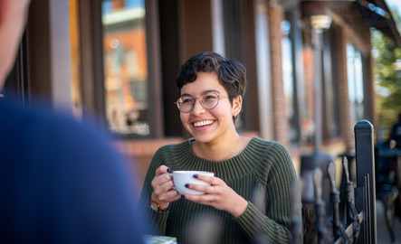 A UW international student sits outside of a local coffee shop and enjoys a coffee with a friend.