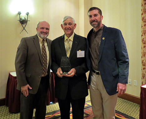 Three men at an awards ceremony. 