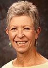 A women with short grey hair wearing a yellow blouse.