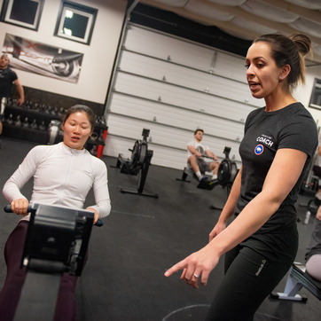 One person directing another person using an exercise machine.