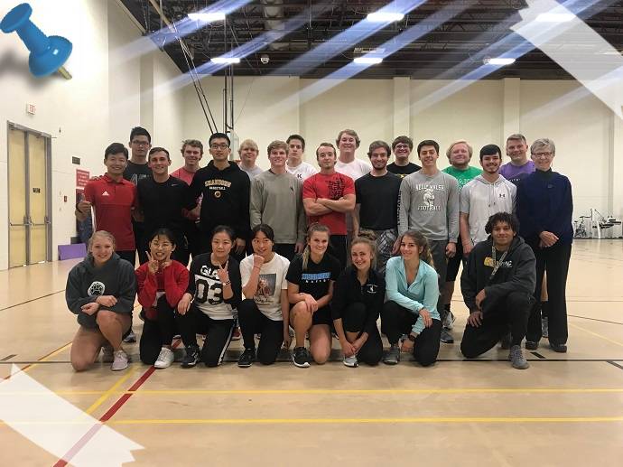 A group of people in a gym standing together and smiling at the camera.