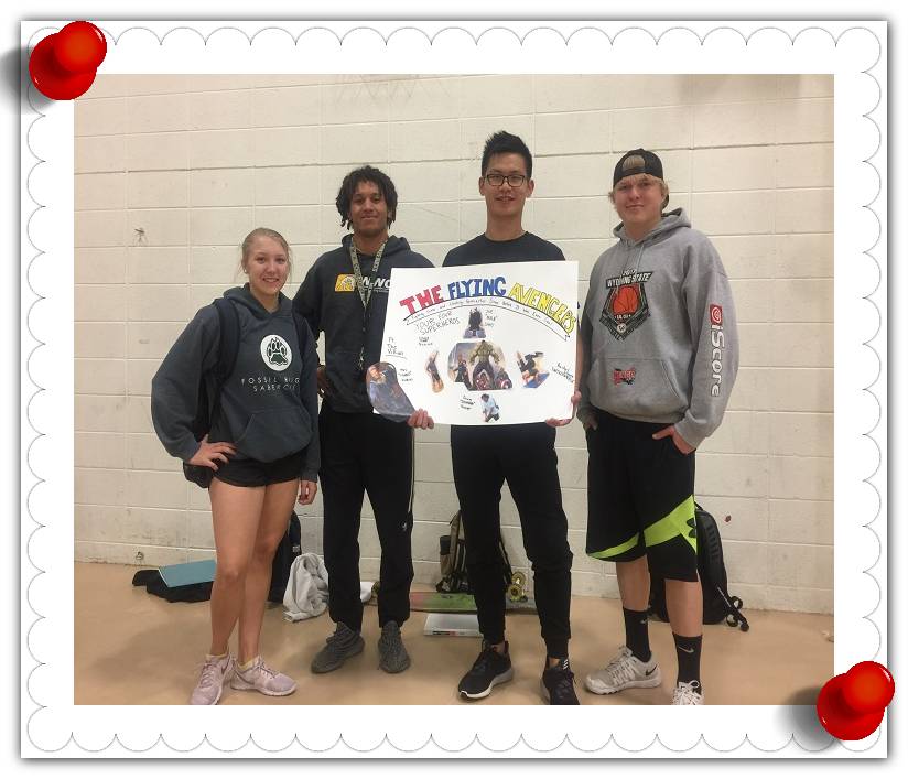 A group of four showing off their handmade team poster.