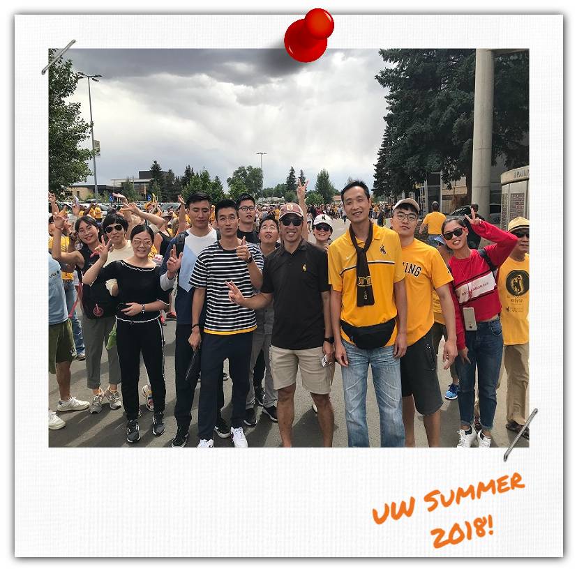 A group of people standing in a parking lot and smiling at the camera.