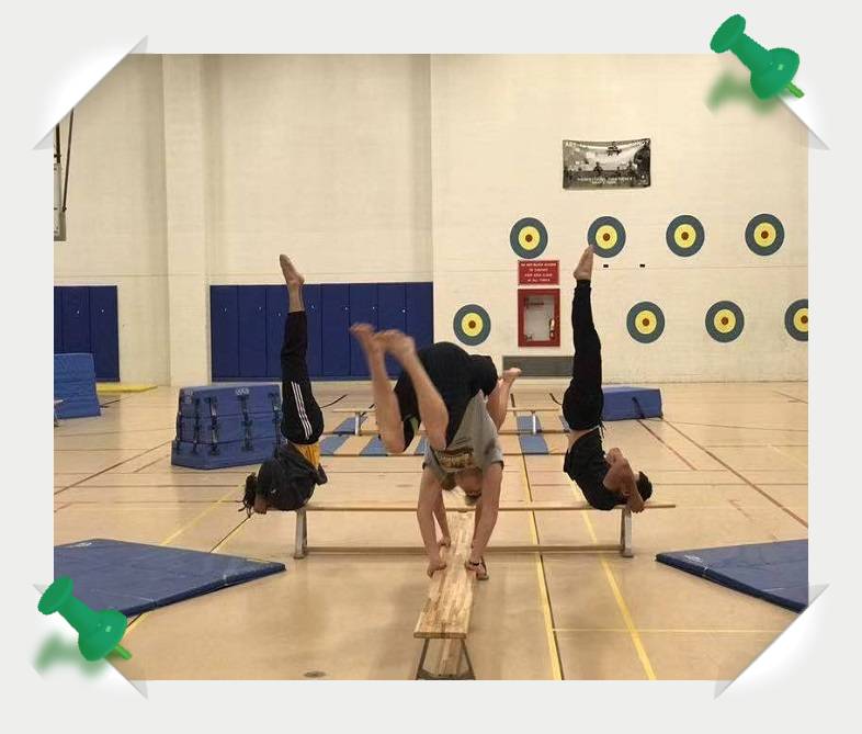 People doing handstands on a gymnastics bar.