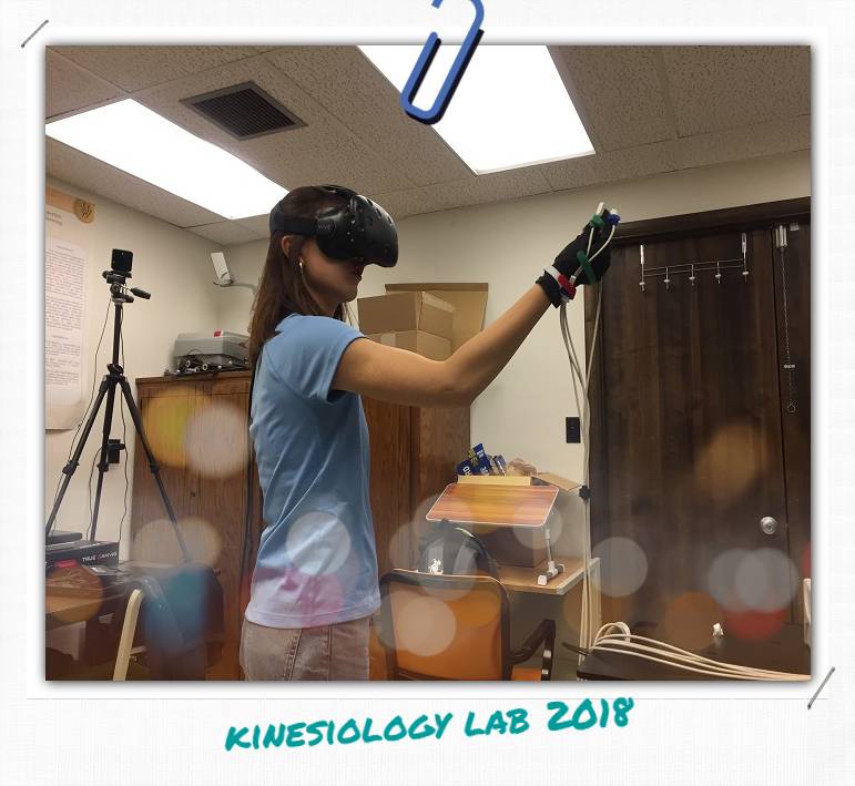 A woman wearing a VR headset, she is wearing a glove that has several cables attached to it.