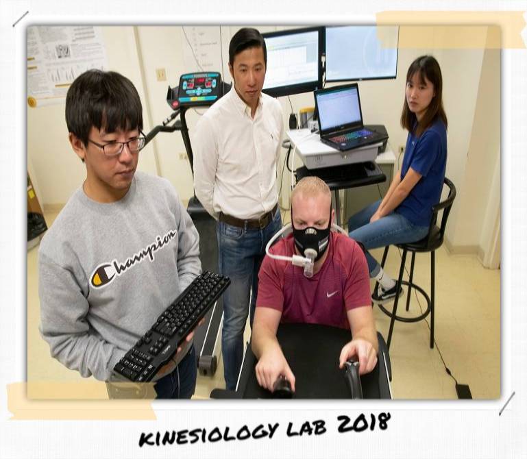 Three people stand at a desk and look at a screen.