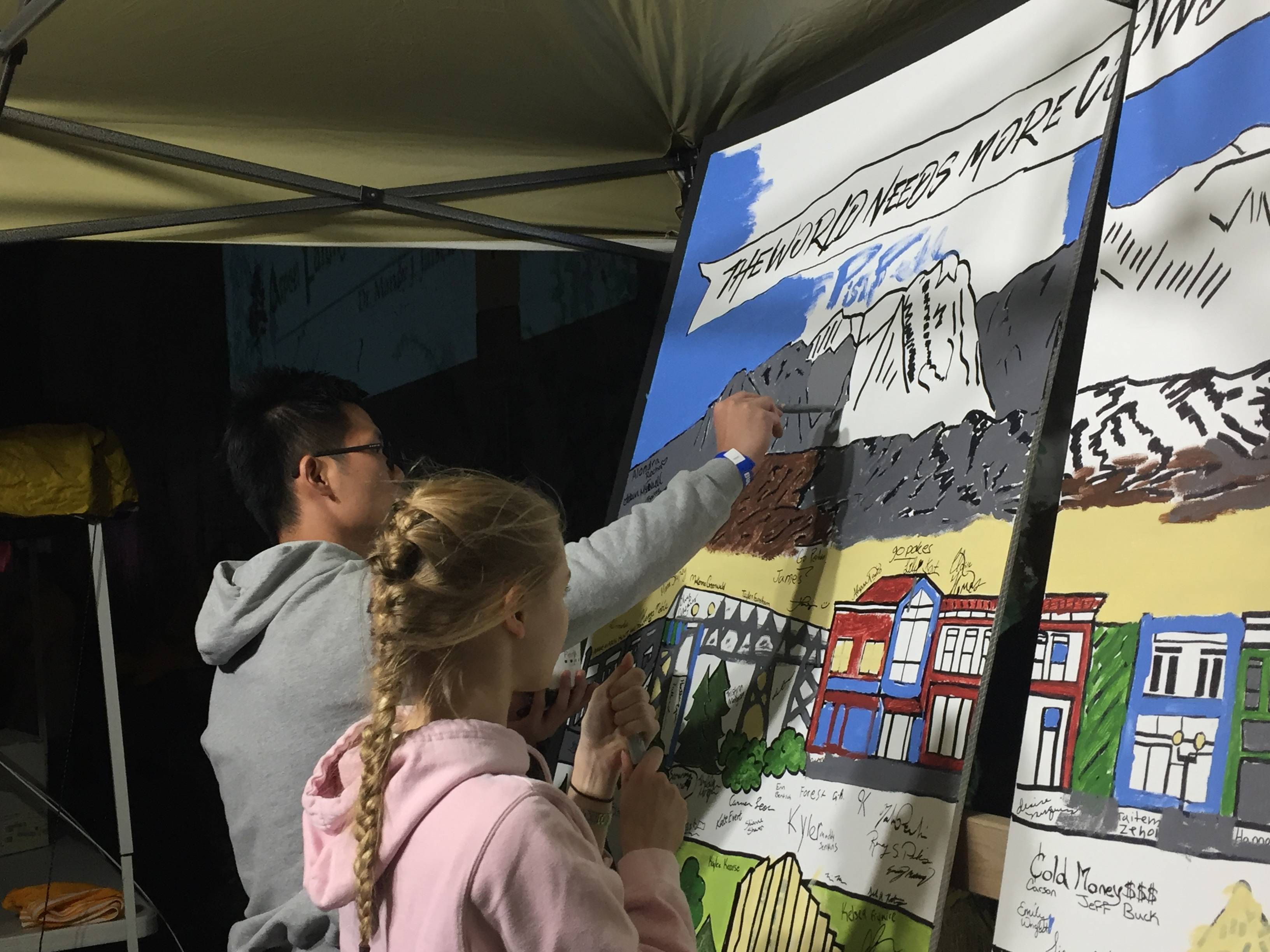 Two people painting a small mural.