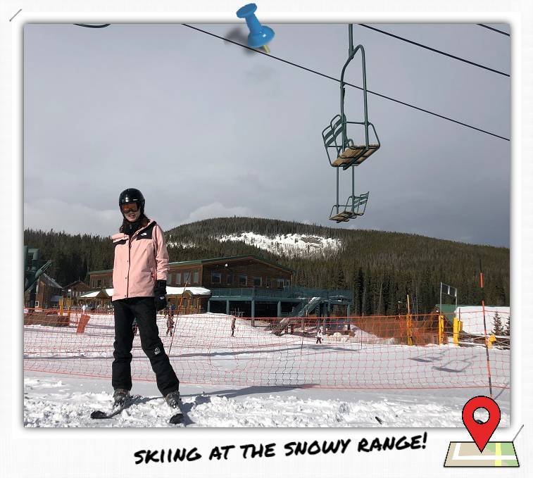 A woman in skiing gear standing below a ski lift.