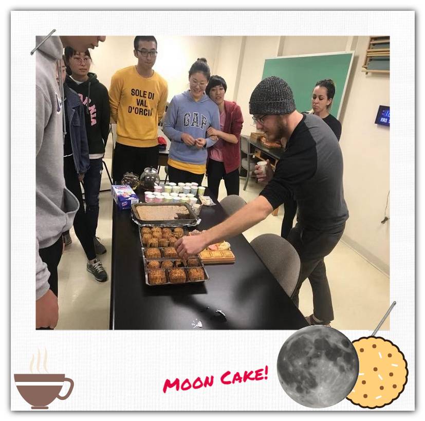 A person picks up a moon cake from a table.